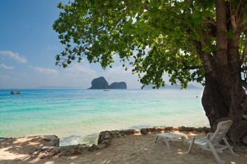 Tropical sea view with island from exotic beach with white beach lounge chair under beautiful large tree Landscape.