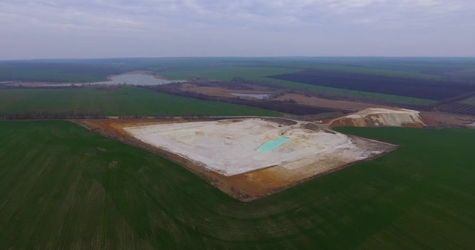 Aerial view of open pit kaolin clay mine (kaolinite quarry) with turquoise pool of water