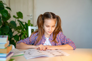 schoolgirl in a plaid shirt studying at home 