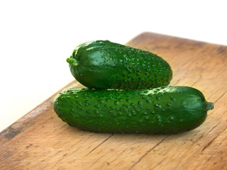 Fresh organic green cucumbers on cloth on a wooden cutting board. vegan healthy food.