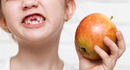 Girl with no milk teeth holding apple closeup