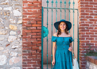 Young and beautiful brunette girl in dress and hat walking outdoor in the street. Nice, France. Summer vacation, traveling and tourism.