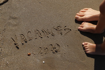inscription sur le sable  avec pieds  vacances 2020
