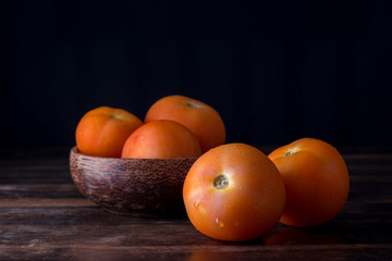 A group of freshly picked tomatoes with dark wooden background.