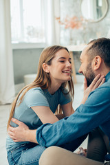 Mirthful hugging couple at home looking happy stock photo