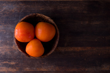 A group of freshly picked tomatoes inside bowl with dark wooden background. Sliced tomatoes. Copy space concept
