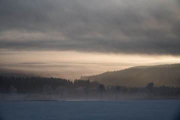 relaxing overcast moudy clouds in a winter valley while sunrise and sundown in a uphill winter scenery with field trees and forest