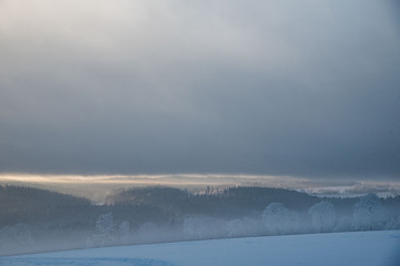 relaxing overcast moudy clouds in a winter valley while sunrise and sundown in a uphill winter scenery with field trees and forest