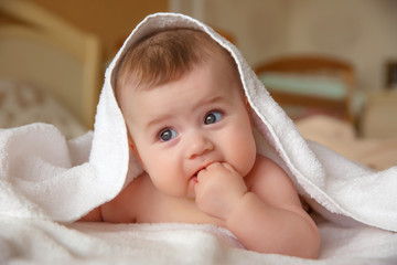 baby is wearing diapers and a white towel in bedroom. A newborn baby is resting in bed after a bath or shower. Children's room. Textiles and bedding for children.