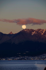 Amazing and breathtaking full moon scenery over Patagonia during early morning with city of...