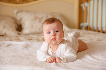 A newborn baby is lying at home in bed smiling.