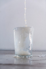 Throwing milk into a glass of water on a white background. Drink macro photography
