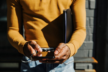 Man texting on a phone by the sidewalk