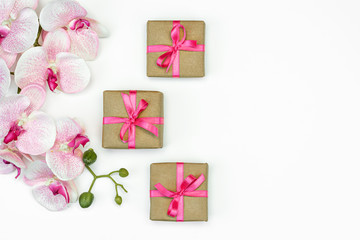 flat lay of Gift present boxes with pink ribbon with orchid flowers on white background top view. Gift or present spring concept. Copy space.