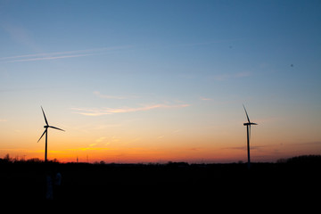 Obraz premium Electric energy windmills against a colorful sunset background creating innovative Alternative energy. Copy space