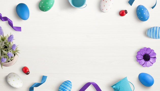 Easter eggs and decorations on white wooden desk. Composition with free space in the middle for promo text