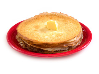 Staple of wheat golden yeast pancakes or crepes on red plate on a white background closeup