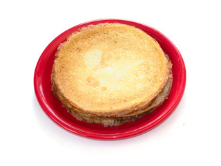 Staple of wheat golden yeast pancakes or crepes on red plate on a white background closeup