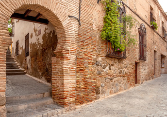Fototapeta premium View of the old streets in Toledo, Spain. Quiet stone pavemented street. Medieval cobbled city.