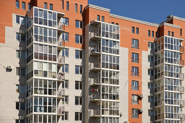Fototapeta premium Lviv, Ukraine - 3 4 2020: Facade of a tall multi-storey modern house with balconies and large glass windows. Design of modern architecture. Top view from the bottom. Modern city architecture