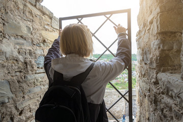 A woman in the castle looks at the city through the bars of an iron window