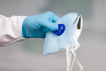 close up of doctor's hand in medical gloves presenting a professional medical face mask