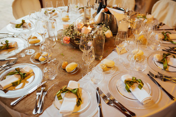 White color wedding table decorated with decorative and elegant for wedding. There are flowers, candles and serving plates on the wedding table. Wedding day, event organization table setting decor.