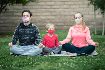 Family practicing yoga wearing cloth face masks. Many countries recommend citizens cover their faces during the world coronavirus covid-19 pandemic.