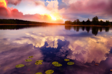 Fantastic sunset on a forest lake. reflection of clouds in the water.