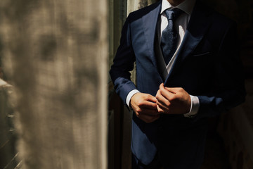 Grooms morning preparation. Cropped photo of elegant young fashion man dressing up for wedding...
