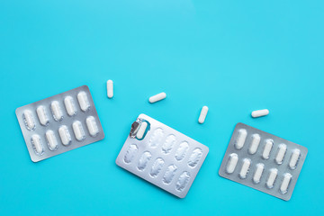 Capsule medicines in blister pack on blue background.