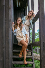 vertical portrait of two pretty girlfriends on the background of an old wooden windmill