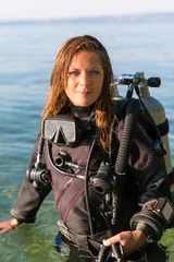 Tuinposter Female Scuba Diving Instructor Standing in Water Wearing a Dry Suit, a Twin Tank and Holding Fins © Angelina Cecchetto