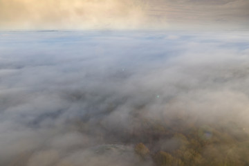 Dream like aerial view between layers of countryside fog and high level cloud in the British countryside