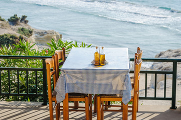 Greek restaurant table on a sea terrace. Restaurant table by the sea. Greek islands vacation in the summer concept.