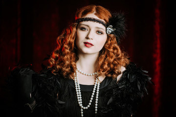 Portrait of old-fashioned red haired woman dressed in style of Great Gatsby era flirting and posing on burgundy velours background. Vintage, flapper party, retro fashion concept