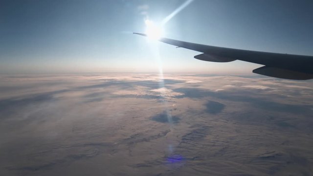 POV passenger: looking out at airplane wing, sun, glare and wind current