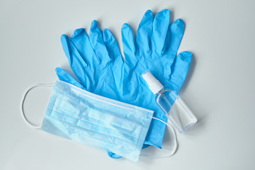 Medical gloves with a sanitizer and a mask on a white table - concept of protection against coronavirus COVID-19.