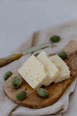 Pieces of white cheese on a wooden cheeseboard. Negative space