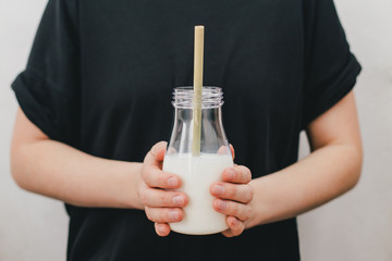Non dairy alternative vegan oat milk in bottle with bamboo eco zero waste straw and fresh oats in woman hands. Gluten and lactose free products.