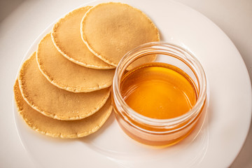 Pancakes on a white plate with honey