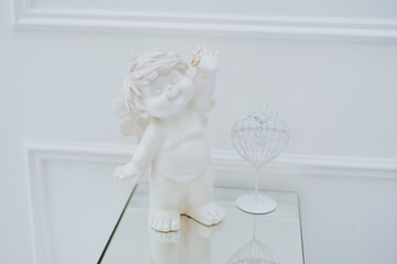 New wedding rings resting on the hands of a cherub surrounded by feathers