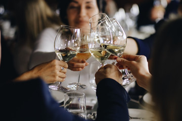Clinking glasses with white wine and toasting.