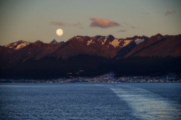 Amazing and breathtaking full moon scenery over Patagonia during early morning with city of...