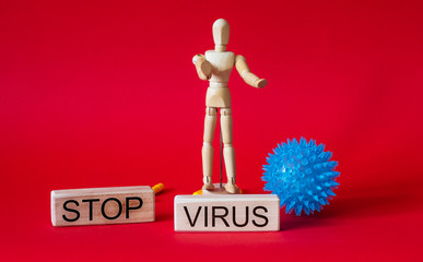 A wooden man stands on the jeng with the words stop virus , next to the caronovirus