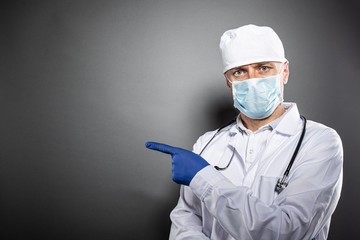 Doctor in white uniform and protective medial mask pointing left