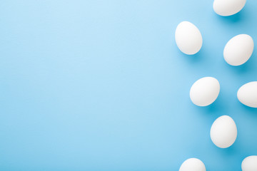 White eggs on light blue table background. Pastel color. Empty place for text. Closeup. Top down view.