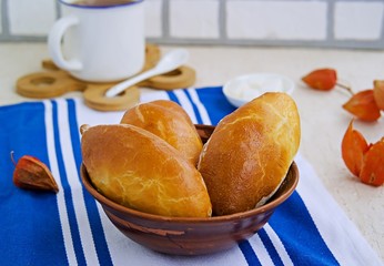 Homemade baked pies from yeast dough with meat in a brown clay bowl on a light concrete background. Russian cuisine. Homemade baking.