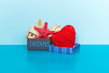 Word Dreams written on gift box, heart, car, house, starfish and pacifier on the blue background.