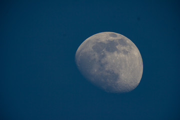 The moon in the telescope in the evening on a dark blue sky background